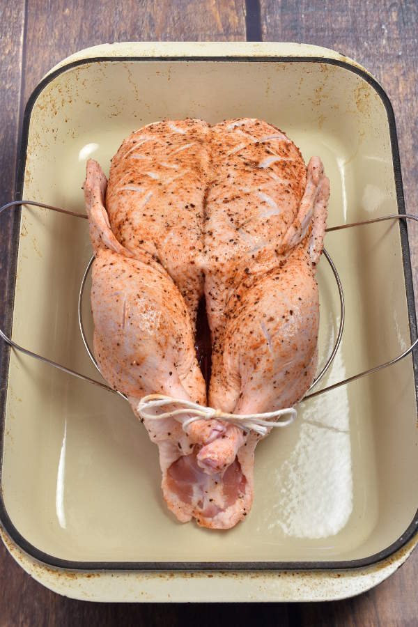 Duck placed over a steamer insert arranged in a roasting pan. 